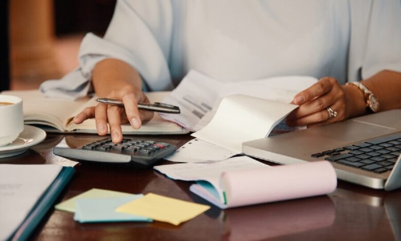 Pessoa revisando documentos e calculando dívidas em uma mesa de escritório, representando o processo de gestão financeira após a morte de um titular.