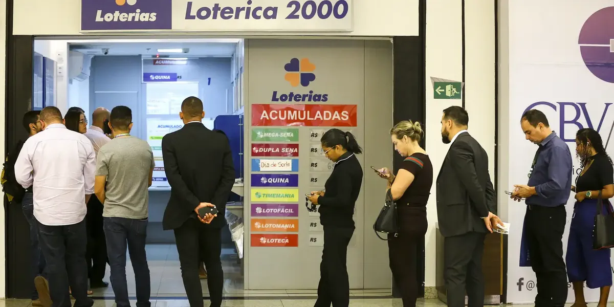 Pessoas aguardam na fila de uma casa lotérica para realizar apostas e pagamentos.