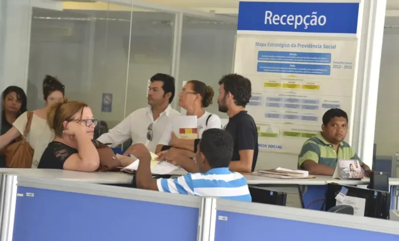 Fila de atendimento no INSS durante a greve dos peritos médicos, com pessoas aguardando para receber benefícios.