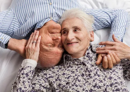 Casal de idosos sorrindo e se abraçando, simbolizando carinho e afeto.