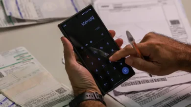 Idoso utilizando calculadora no celular para realizar cálculos financeiros sobre dívidas