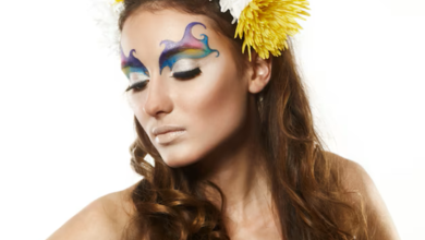 Mulher com maquiagem artística colorida e flores no cabelo, celebrando o Carnaval com um look vibrante.