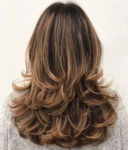 Mulher com cabelo longo e em camadas, com luzes suaves