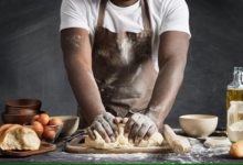 Homem amassando massa de pão na cozinha.