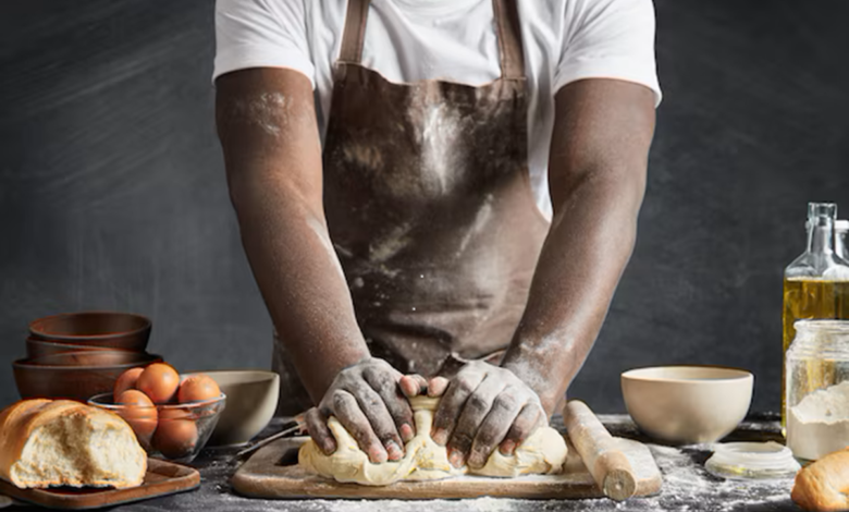 Homem amassando massa de pão na cozinha.