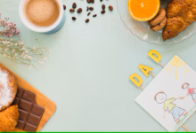 Café da manhã com croissants, chocolate, café, frutas e decoração com letras e desenho de pai e filho.