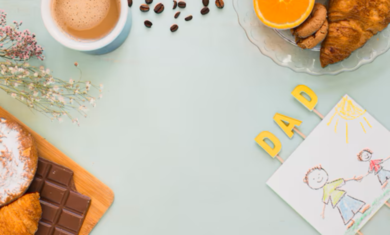 Café da manhã com croissants, chocolate, café, frutas e decoração com letras e desenho de pai e filho.