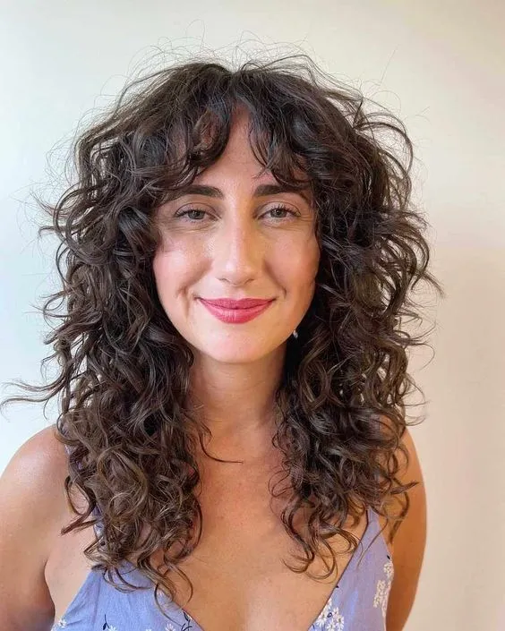 Mulher com cabelo cacheado e corte Kitty Cut, tendência moderna para 2025