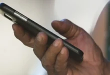 Mão segurando um celular, com foco no processo de gerenciar a "lixeira" do WhatsApp para liberar espaço.