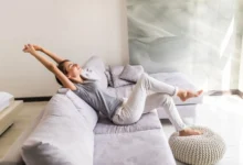 Mulher relaxando em um sofá em uma sala bem iluminada e arejada