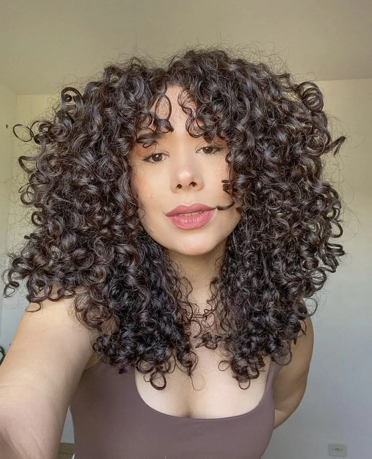  Mulher com cabelo cacheado volumoso exibindo o corte Marquise Layers.