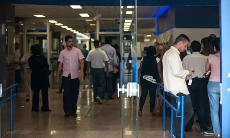 Pessoas em fila dentro de uma agência bancária, simbolizando a movimentação nas agências durante alterações no funcionamento.