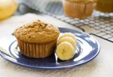 Muffin de banana servido com rodelas de banana em um prato, uma opção deliciosa para um lanche saudável.