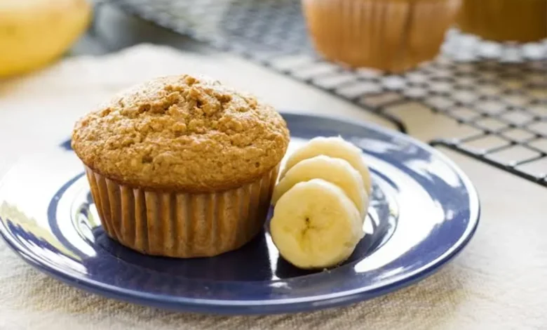 Muffin de banana servido com rodelas de banana em um prato, uma opção deliciosa para um lanche saudável.