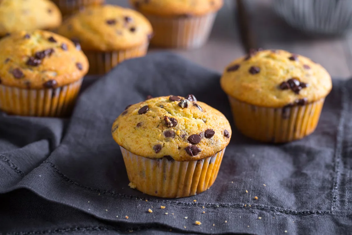 Muffins de banana com gotas de chocolate, servidos sobre um prato, uma versão criativa e deliciosa para o lanche.