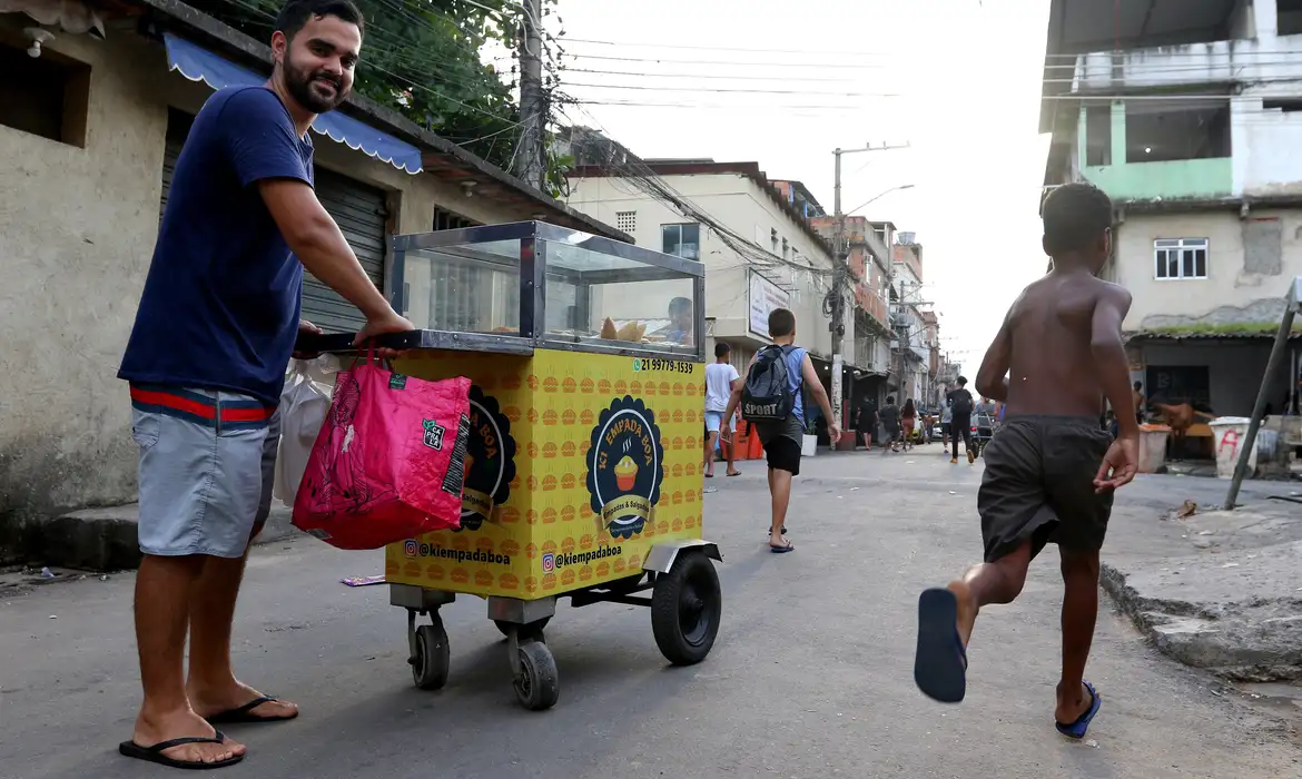 Vendedor ambulante com carrinho em rua de comunidade.