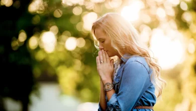 Mulher em oração ao ar livre com a luz do sol ao fundo