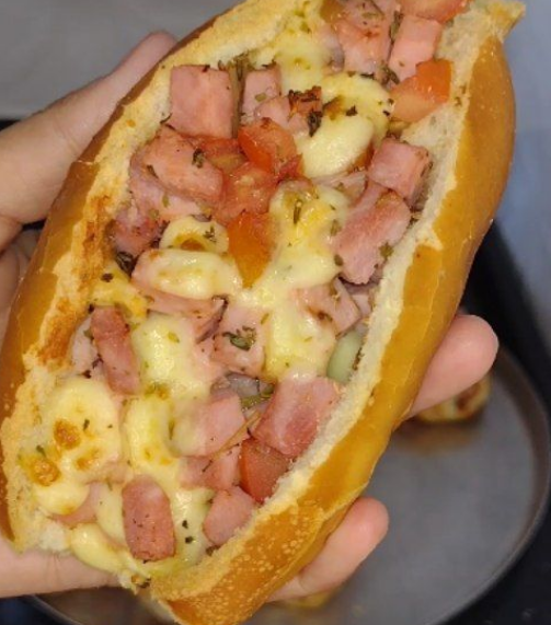 Sanduíche recheado com presunto, queijo e tomate, preparado com espaço para mais recheio delicioso