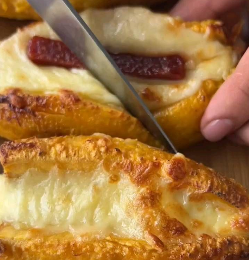 Pão recheado com goiabada e queijo sendo cortado ao meio, mostrando recheio derretido