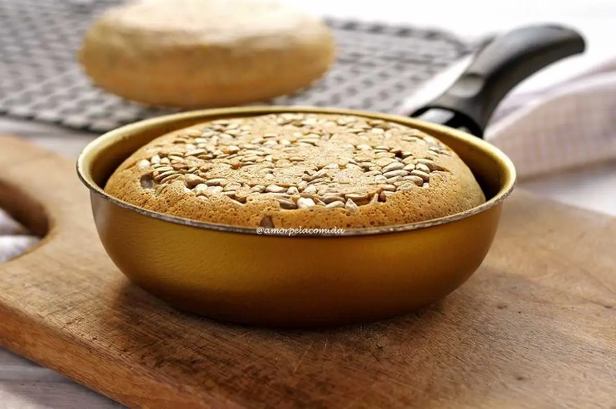 Pão de aveia sendo preparado na frigideira com sementes de girassol, uma variação personalizada da receita.