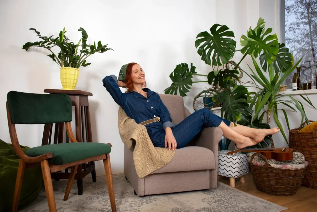 Mulher relaxando em uma poltrona cercada por plantas em um ambiente aconchegante