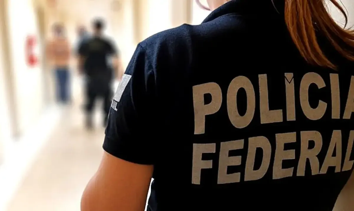 Agente da Polícia Federal em corredor durante operação contra fraudes no INSS.
