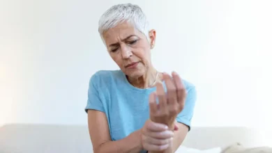 Mulher idosa segurando o pulso, representando os impactos da osteoporose.