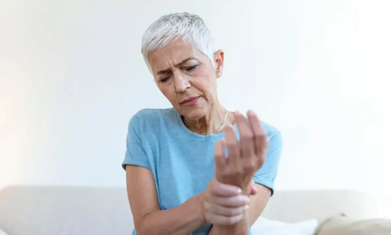 Mulher idosa segurando o pulso, representando os impactos da osteoporose.