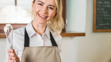 Chef sorridente segurando um fouet com creme, pronta para preparar uma sobremesa deliciosa.