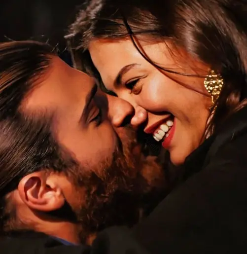 Casal apaixonado sorrindo em um momento romântico em um ambiente descontraído.