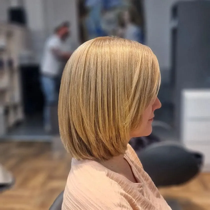 Mulher com corte soft bob, cabelo suave e volumoso, visto de lado em um salão de cabeleireiro.