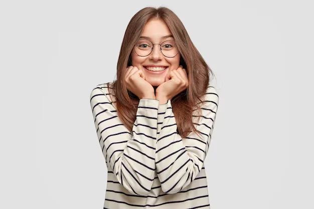 Mulher sorrindo e segurando o rosto com as mãos, usando óculos de grau.