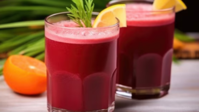 Dois copos de suco de cenoura e beterraba decorados com fatias de limão e folhas de hortelã.