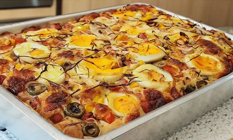 Torta portuguesa assada em uma forma, com cobertura de ovos, presunto, cebola e azeitonas.