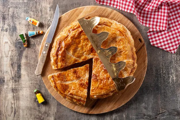 Torta do rei com uma fatia cortada, decorada com uma coroa, simbolizando a tradição da culinária.