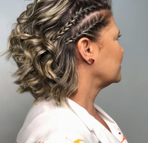 Mulher com cabelo curto e ondulado, usando tranças laterais.