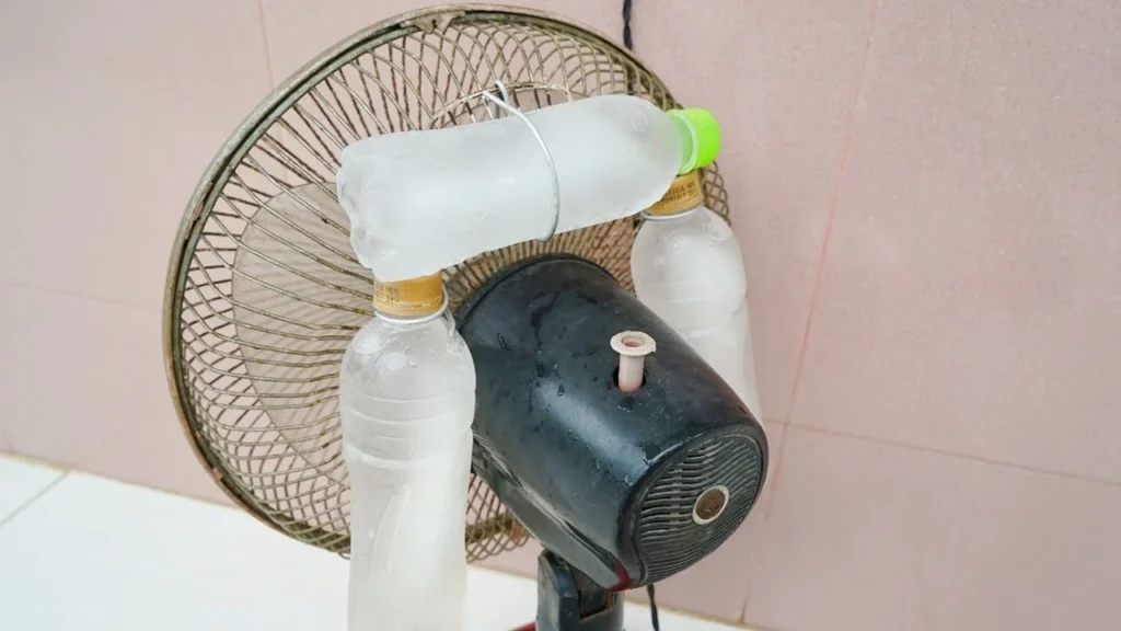 Ventilador com garrafas congeladas presas a ele, criando um truque para esfriar o ambiente