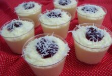 Mousses de coco cremosos servidos em copinhos, decorados com coco ralado e geleia de frutas vermelhas.