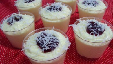 Mousses de coco cremosos servidos em copinhos, decorados com coco ralado e geleia de frutas vermelhas.