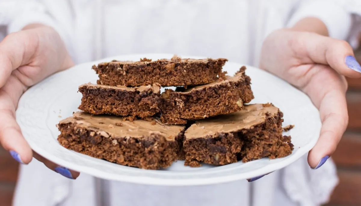 Porção de bolo de chocolate com nozes, servido em um prato, destacando uma variação da receita tradicional.