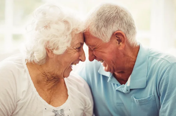 Casal de idosos rindo juntos, demonstrando felicidade e diversão.