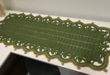 Caminho de mesa de crochê verde com acabamento dourado, trazendo sofisticação e requinte para a decoração da casa.