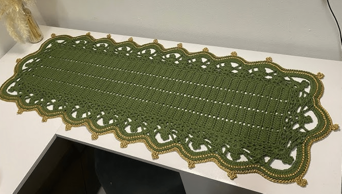 Caminho de mesa de crochê verde com acabamento dourado, trazendo sofisticação e requinte para a decoração da casa.