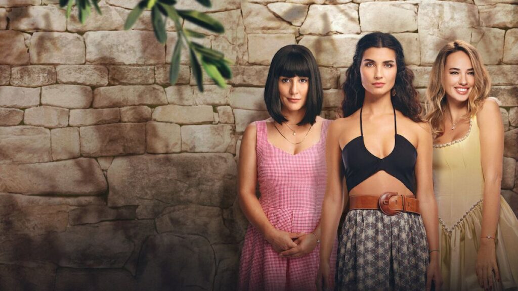 Três mulheres com diferentes estilos de roupas posando em frente a um muro, cena da novela turca 'Uma Nova Mulher'.