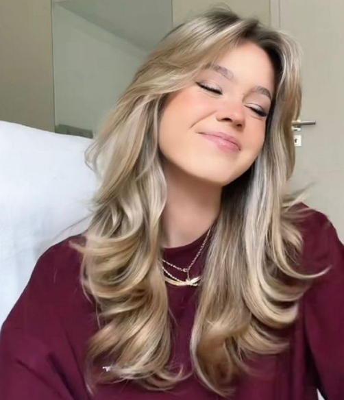 Mulher com cabelo estilo corte borboleta, com camadas e brilho natural.