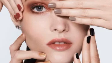 Mulher com unhas coloridas em diferentes tons de esmalte, incluindo vermelho, nude, dourado e preto