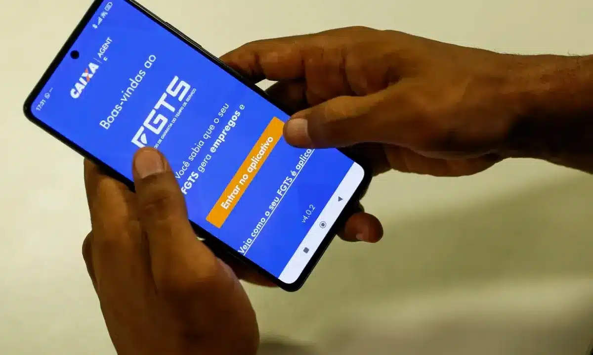 Pessoa acessando o aplicativo do FGTS no celular para consultar saldo e verificar possíveis valores a receber.