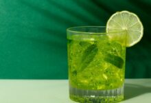 Copo de caipirinha verde com limão e folhas de hortelã, símbolo de uma caipirinha bem feita.