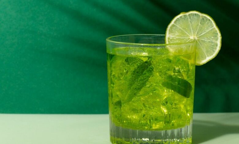 Copo de caipirinha verde com limão e folhas de hortelã, símbolo de uma caipirinha bem feita.