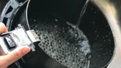 Pessoa limpando a cesta da air fryer com água, erro comum durante a limpeza do aparelho